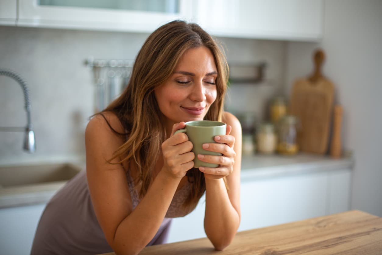 Mulher desfrutando de uma xícara de café em sua cozinha.