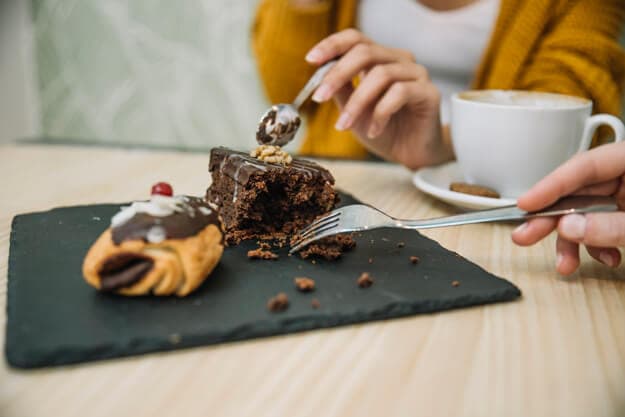 duas pessoas comendo um pedaço de bolo de chocolate