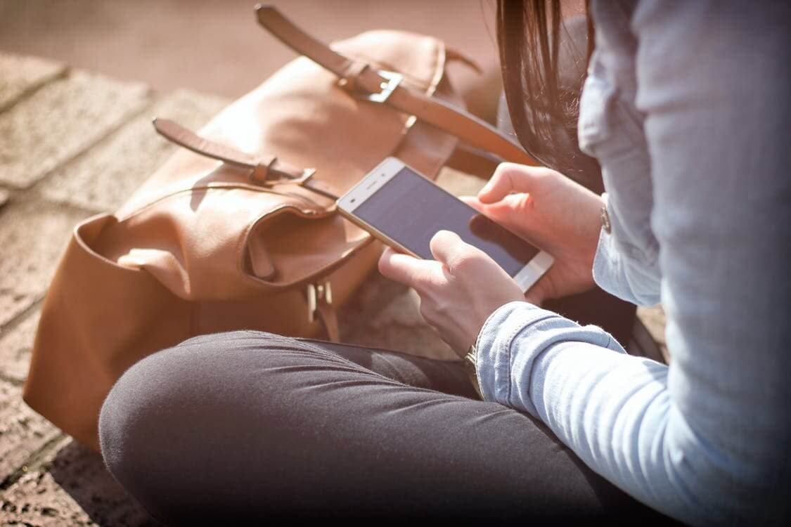menina sentada usando o celular