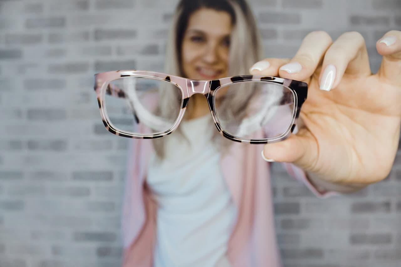Mulher segurando um óculos depois da blefaroplastia