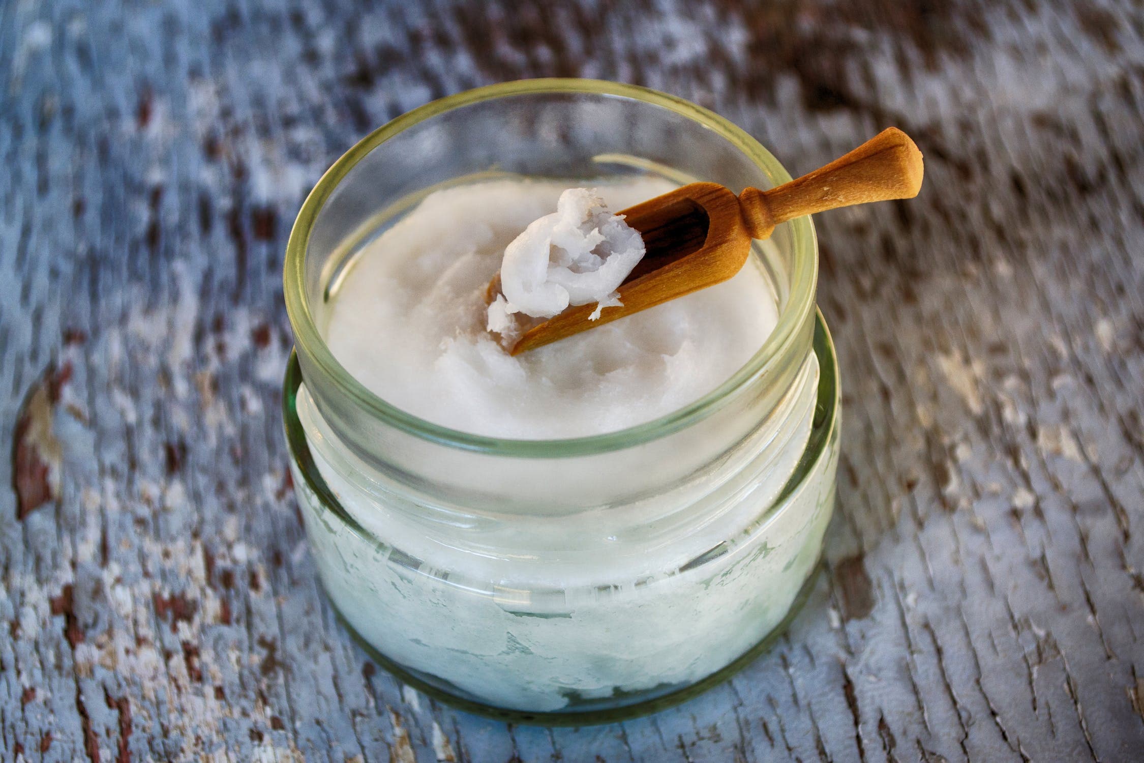 Na imagem é possível ver um pote de creme, com uma pequena espátula dentro