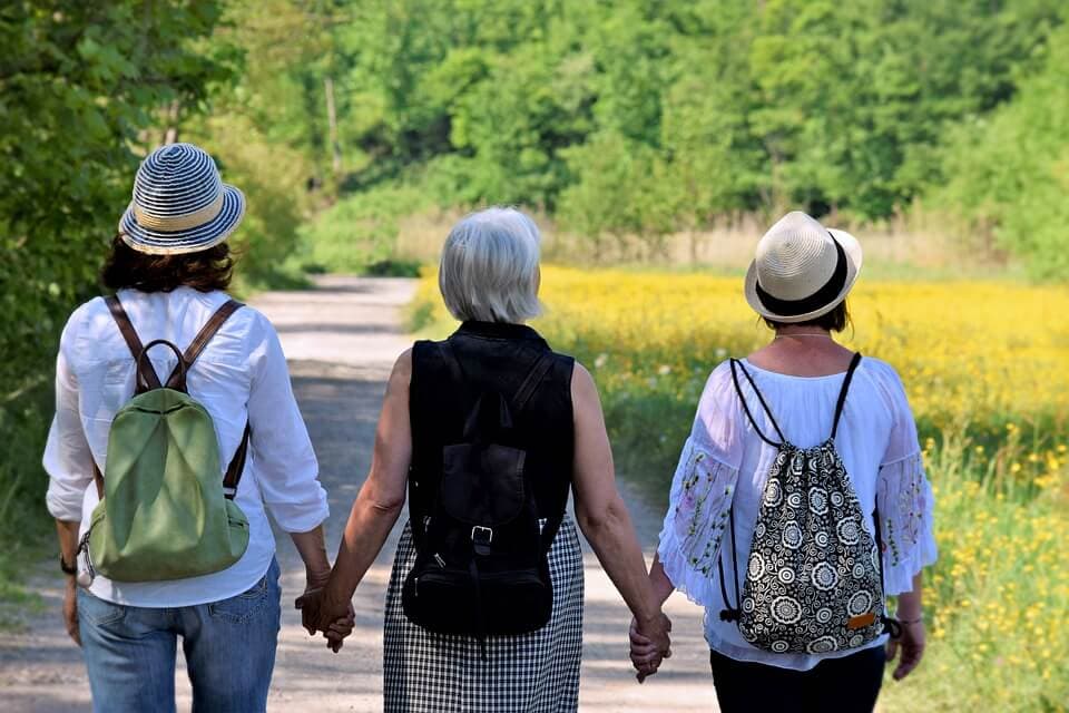 mulheres de costas de mãos dadas caminhando
