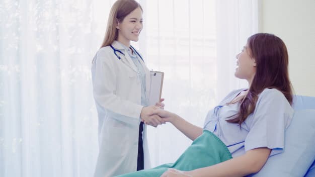 médica apertando a mão da paciente deitada na maca