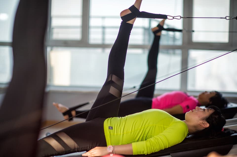 Mulher deitada no chão fazendo exercício de pilates para a perna.