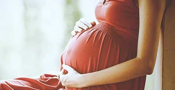 Mulher grávida com a mão na barriga