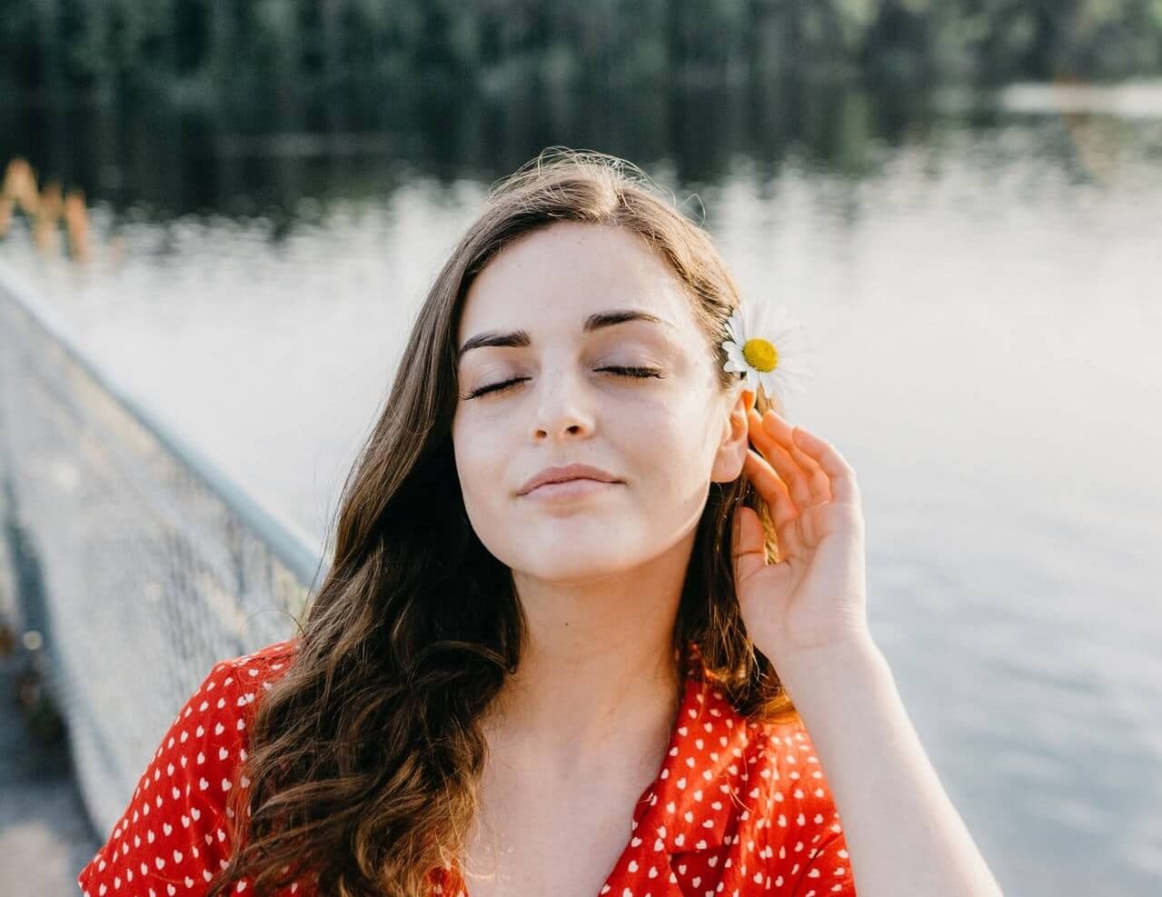 Mulher com os olhos fechados e sorriso entreaberto