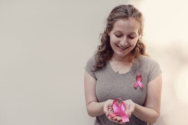 Mulher segurando fitas rosas para simbolizar o outubro rosa