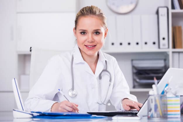 médica sentada no consultório anotando informações