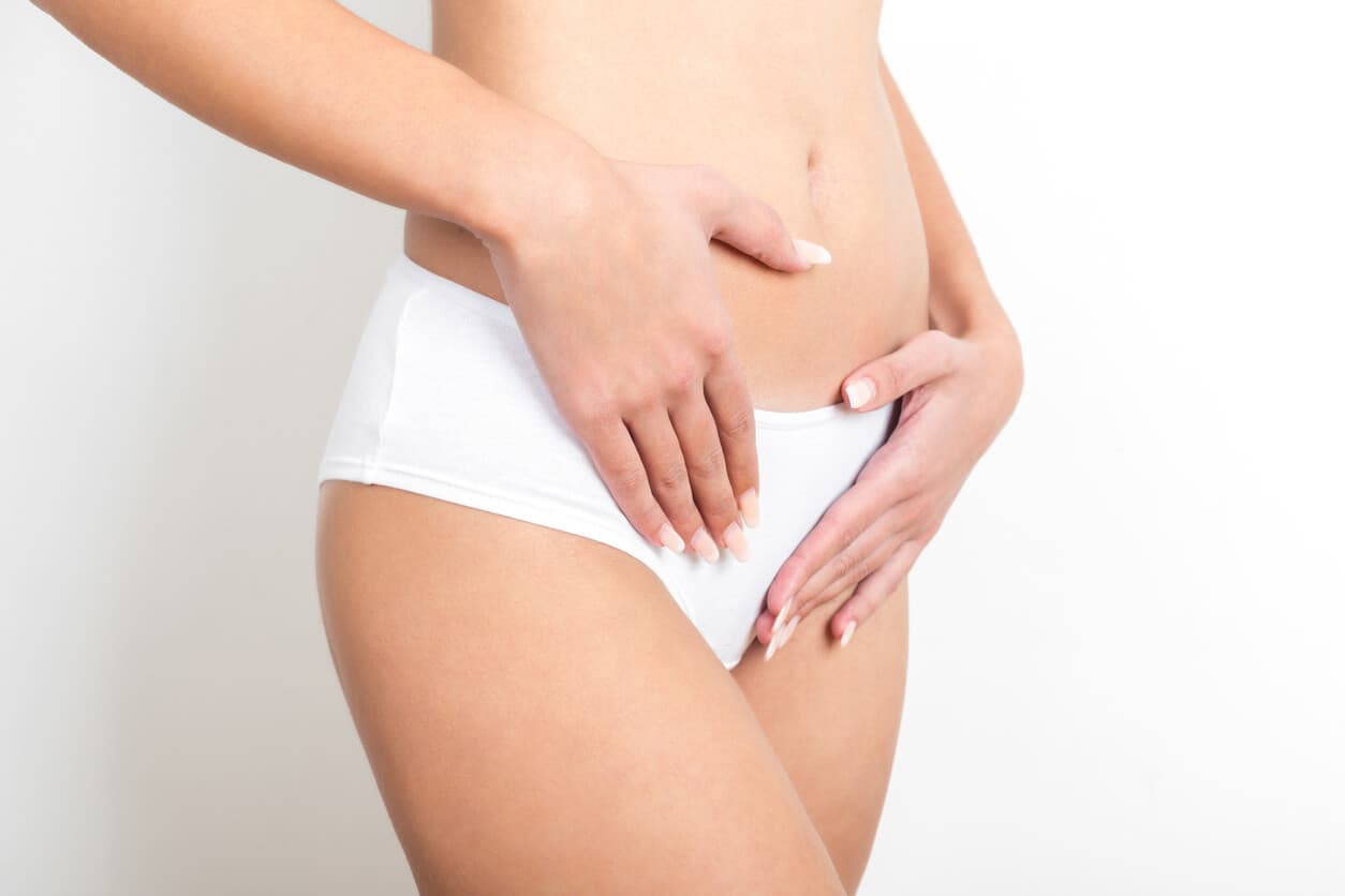 Mulher em roupas íntimas brancas com as mãos no ventre