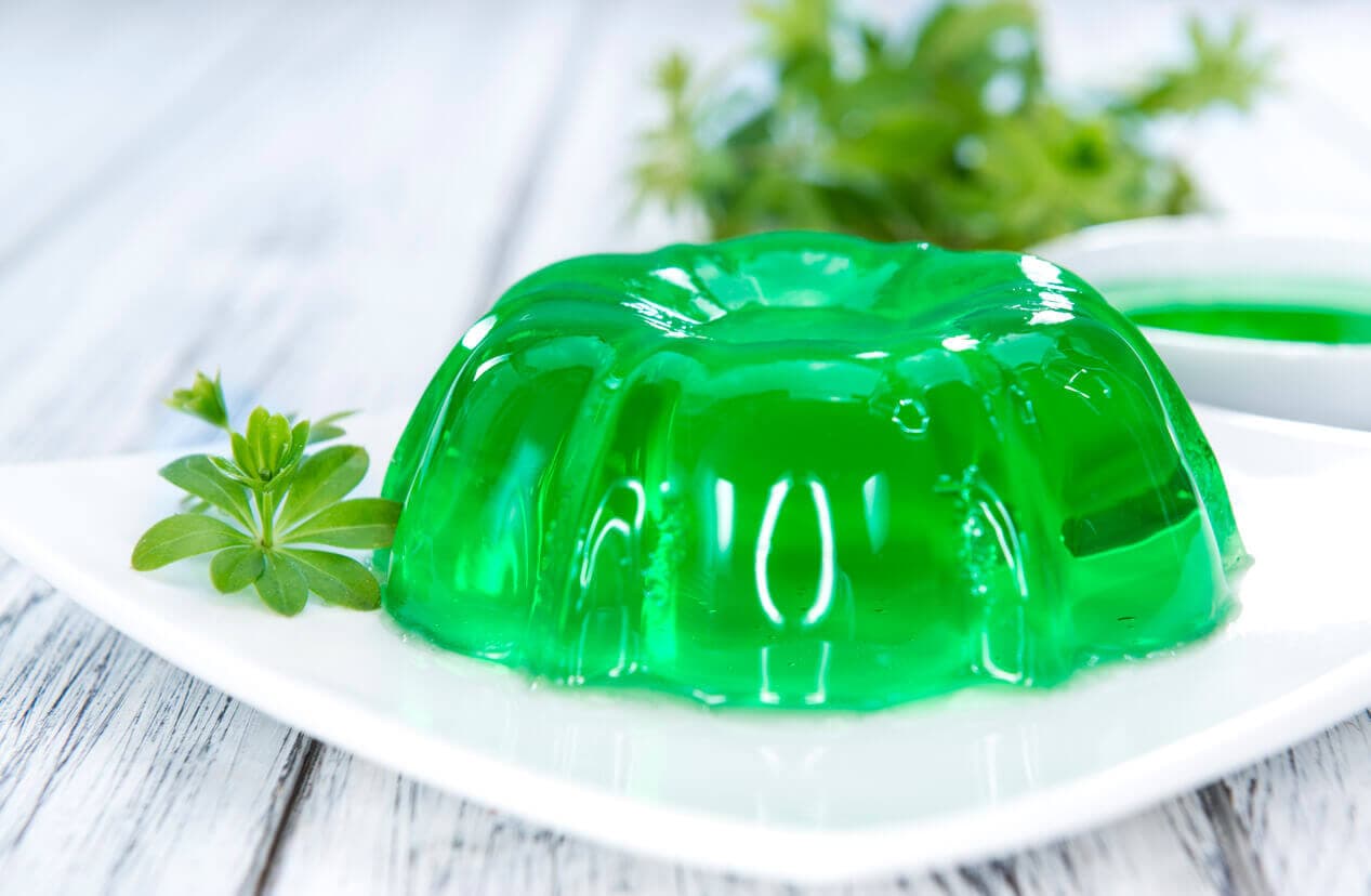 Sobremesa de gelatina verde em um prato branco, exemplo de um alimento rico em colágeno