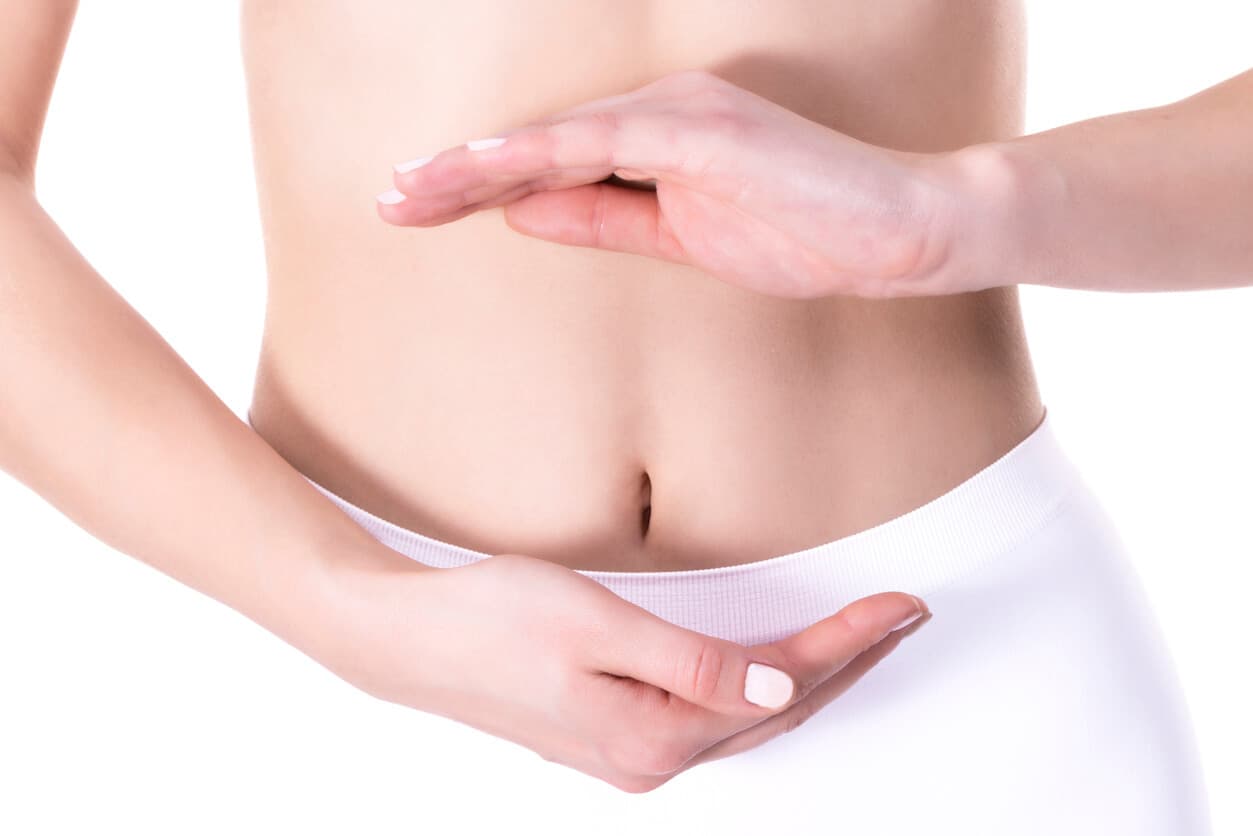 Close uma mulher com as mãos em circulo ao redor do umbigo