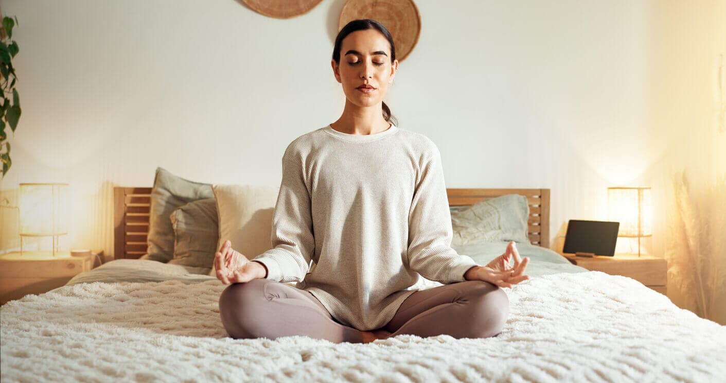 Mulher praticando meditação em casa como técnica natural para controlar a ansiedade pré-cirurgia.