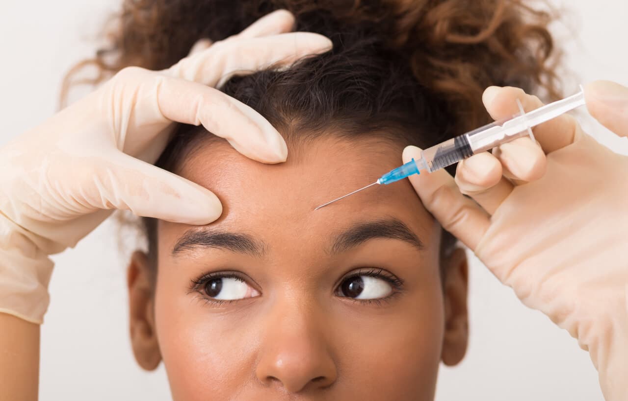 Mulher recebendo uma injeção de toxica botulínica na testa