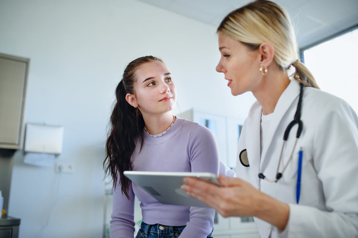 Adolescente e médica conversando em consultório médico
