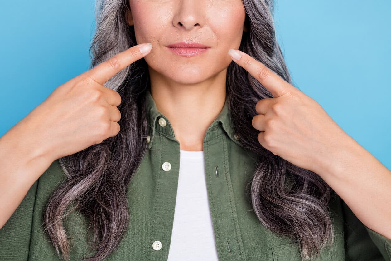 Mulher apontando para os lábios, ilustrando o procedimento de lip lift