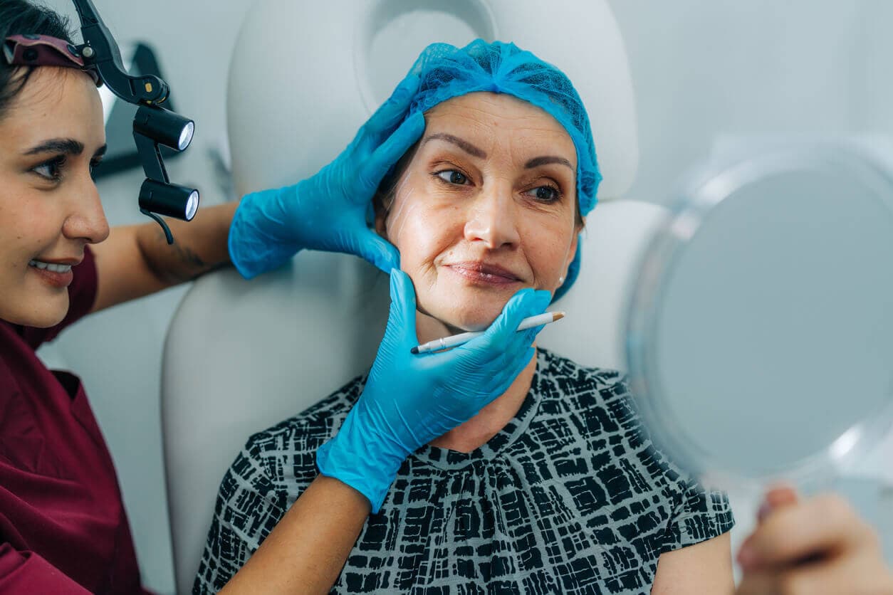 Médica avalia o rosto de paciente antes de procedimento estético.