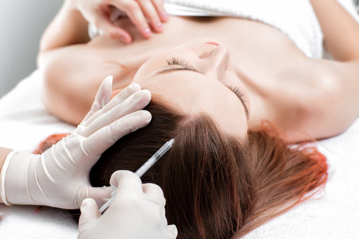 Profissional médico realizando aplicação de microinjeção em paciente durante mesoterapia capilar