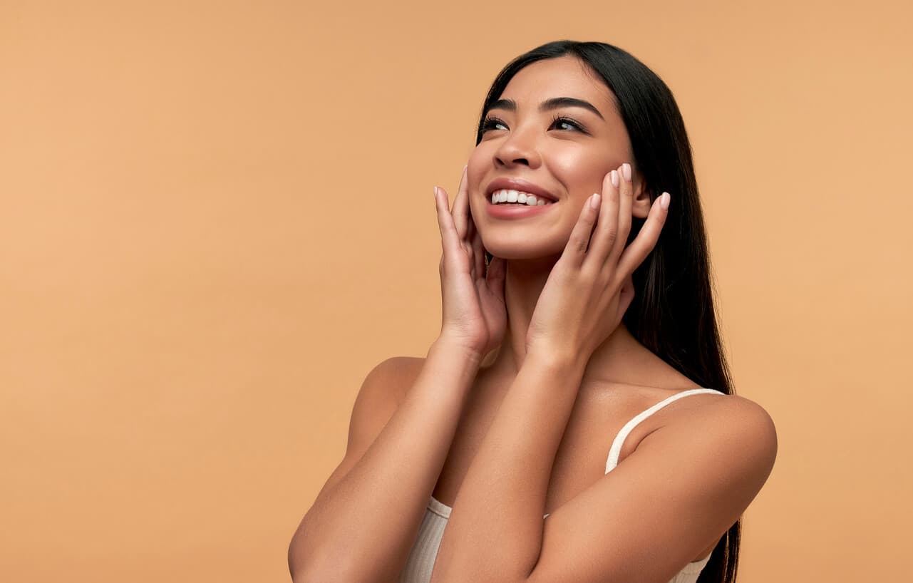Mulher jovem sorrindo e tocando suavemente as laterais do rosto