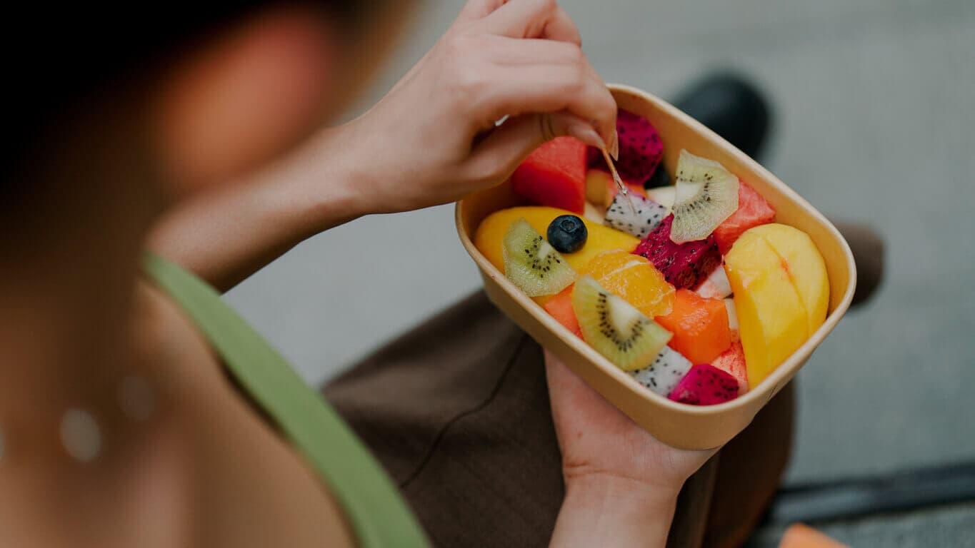 Mulher comendo uma salada de frutas