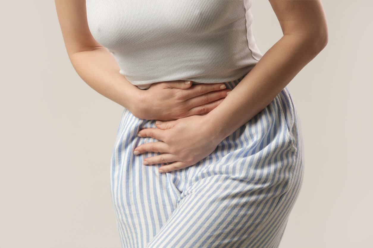 Mulher com as mãos no abdômen, ilustrando desconforto causado pela prisão de ventre pós-cirúrgico.