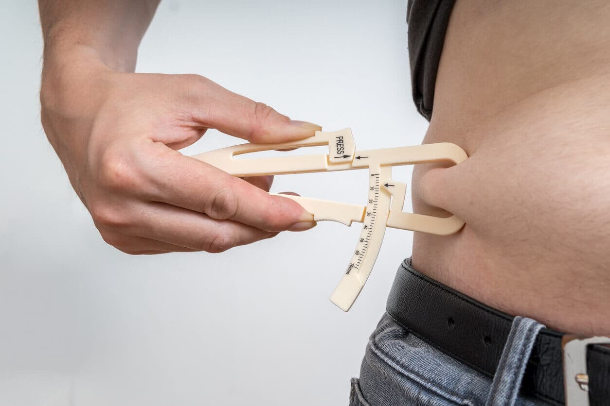 Homem medindo excesso de gordura e flacidez abdominal na barriga