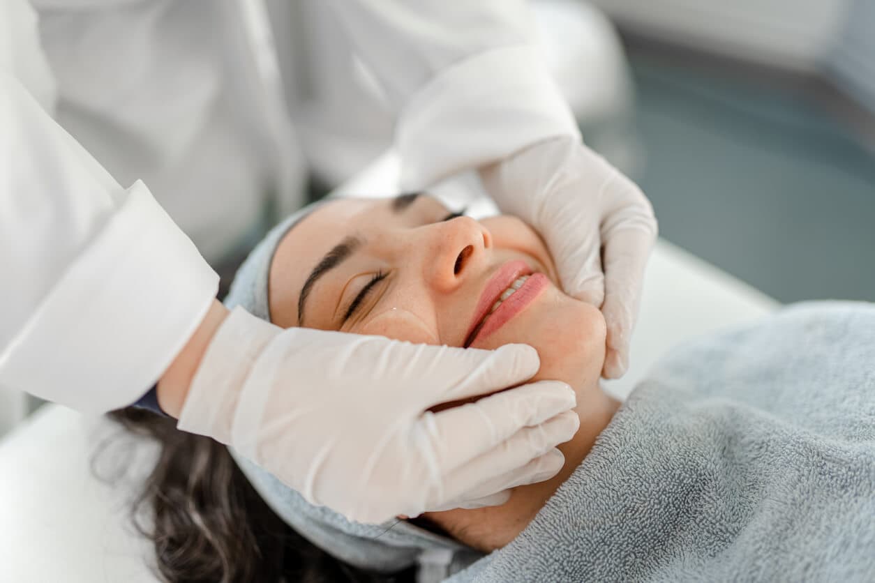 Mulher jovem sorridente deitada em cama hospitalar antes de procedimento cirúrgico