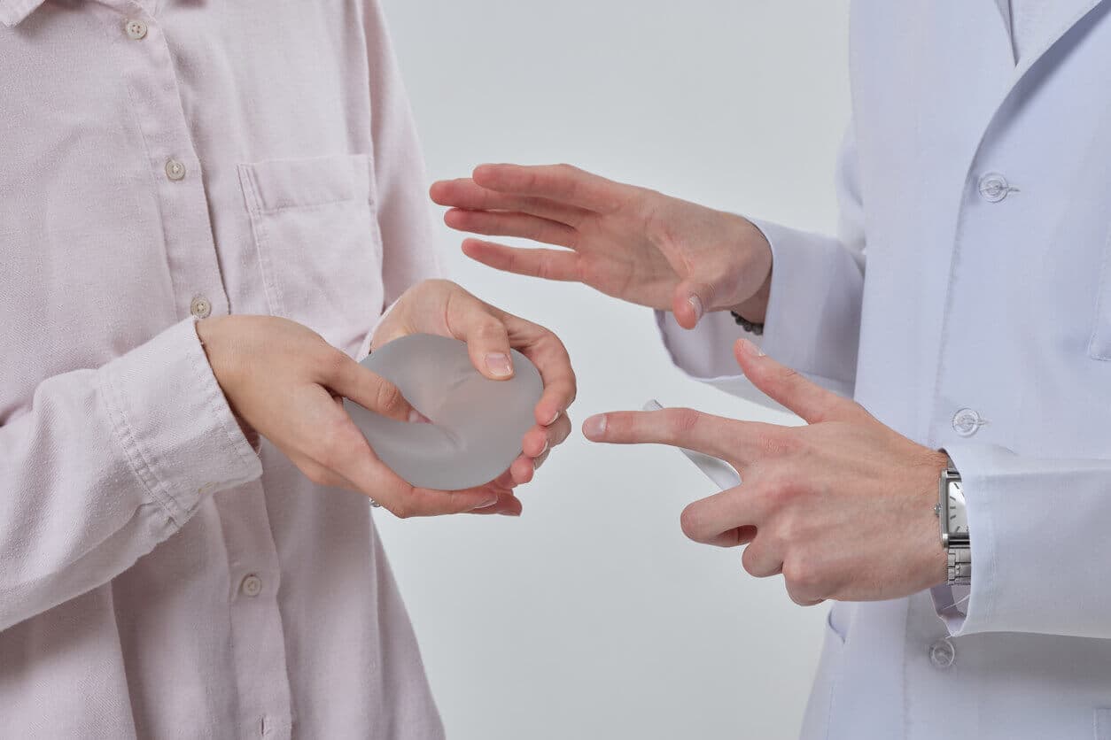 Cirurgião plástico profissional mostrando implantes mamários de silicone para sua paciente