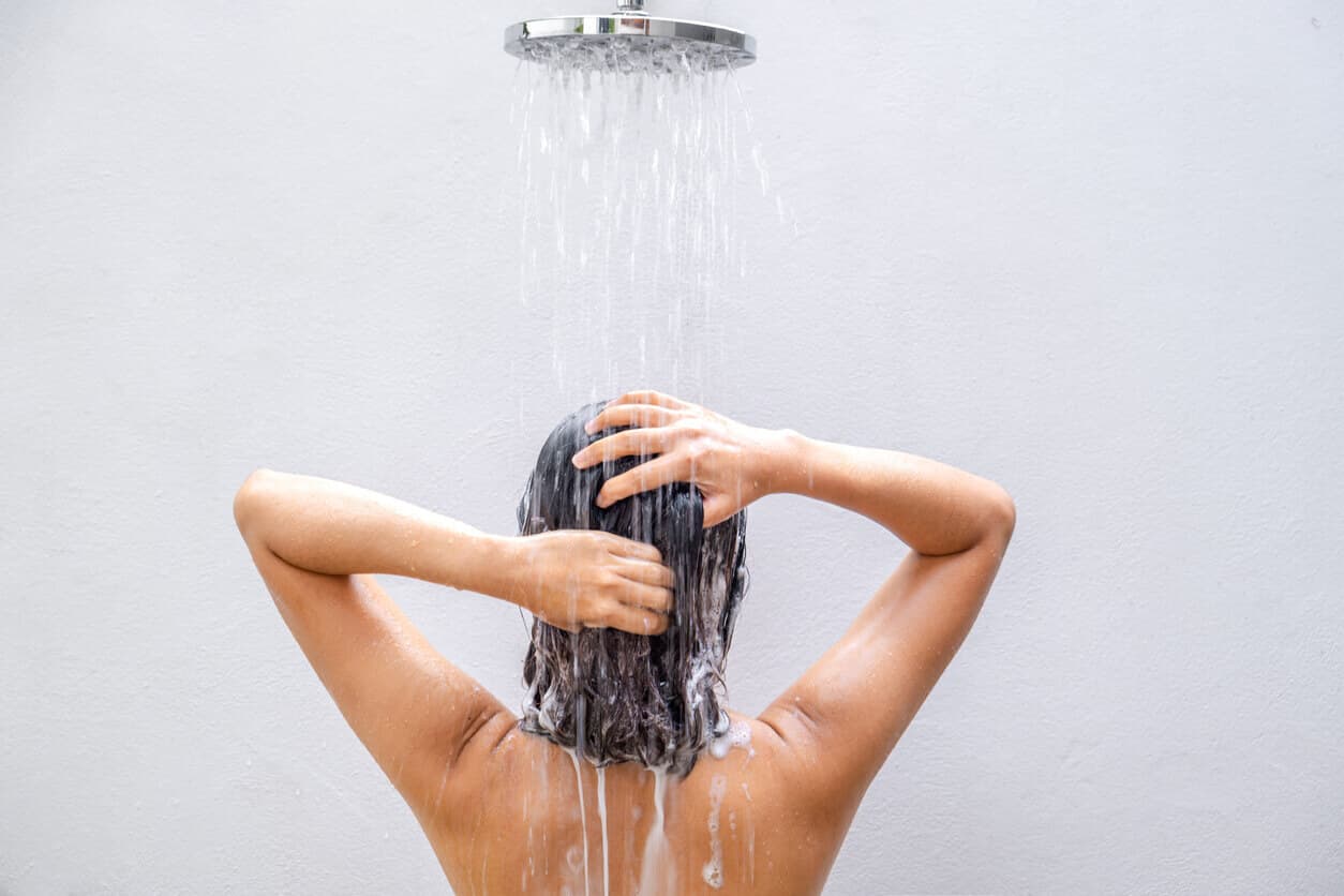 Mulher de costas lavando o cabelo
