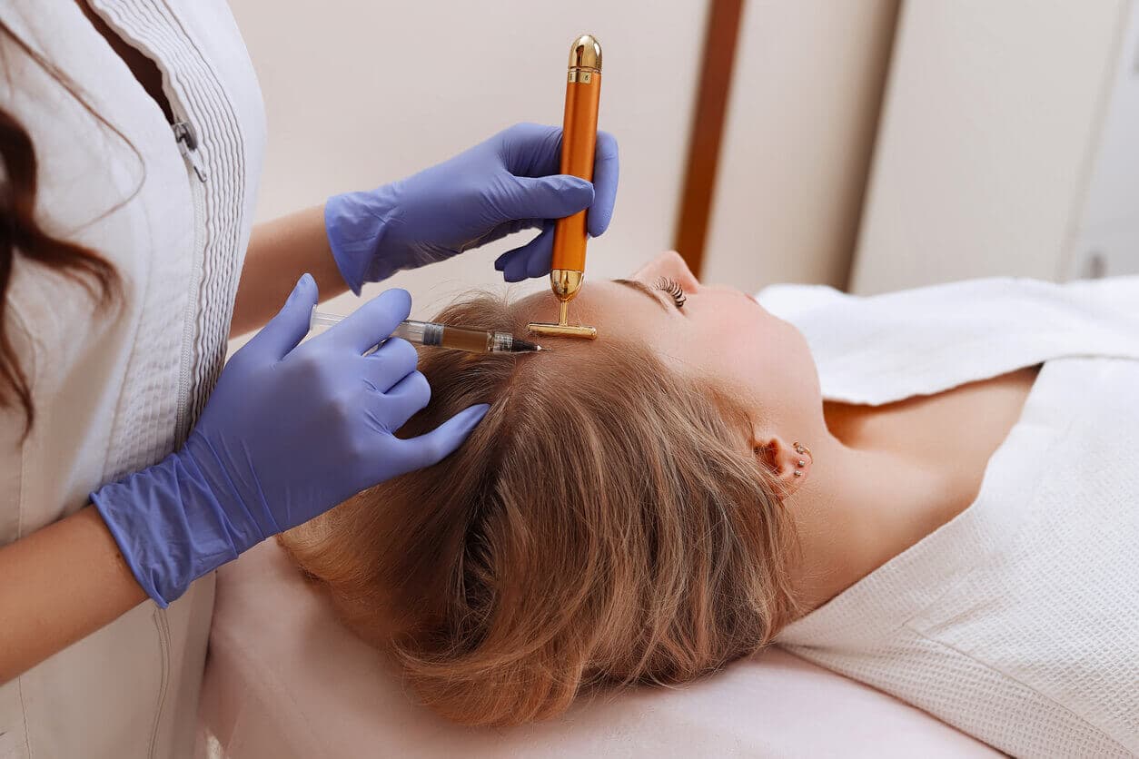 Médica realizando um tratamento de terapia capilar para queda de cabelo em uma paciente jovem do sexo feminino