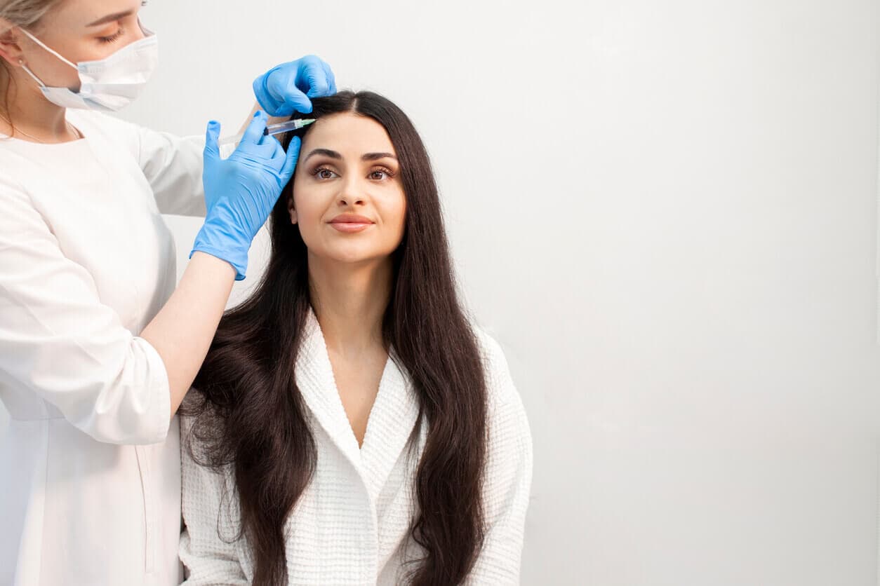 Mulher recebendo aplicação de terapia injetável no couro cabeludo, representando PRP, mesoterapia ou células-tronco contra queda de cabelo.