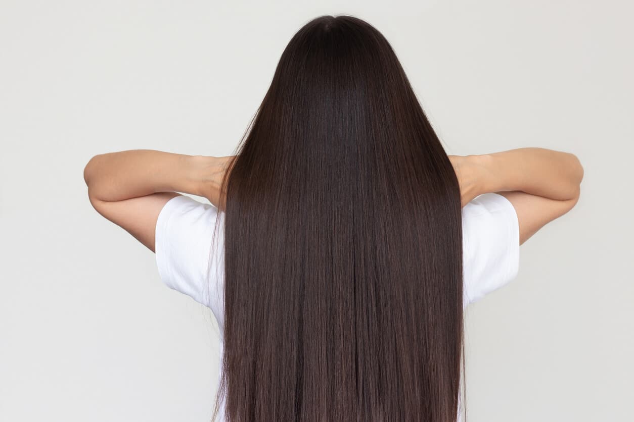Mulher de cabelos longos e lisos exibindo fios saudáveis após transplante capilar natural