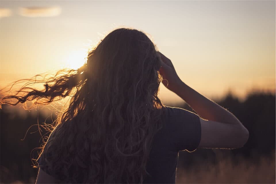 Mulher de costas olhando para um pôr do sol