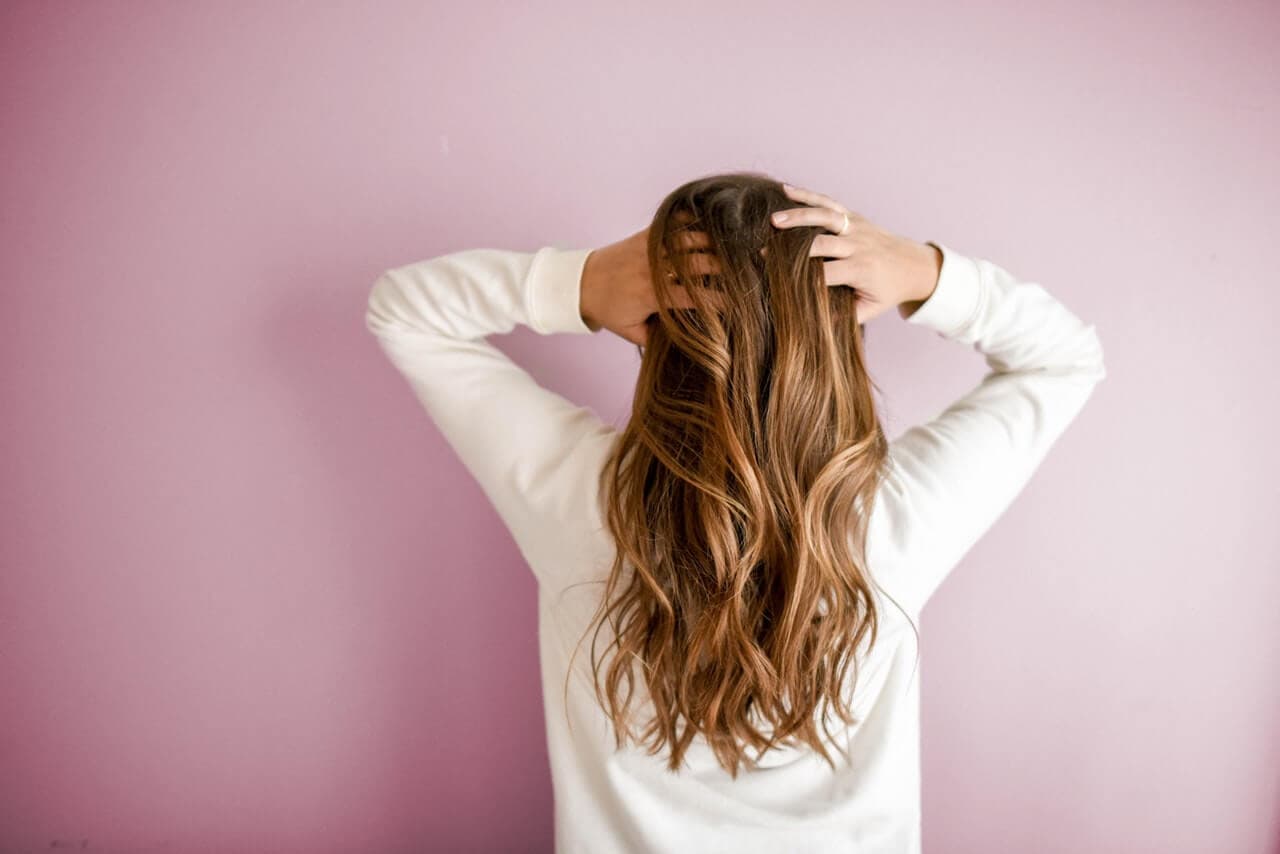 Mulher de costas segurando os cabelos